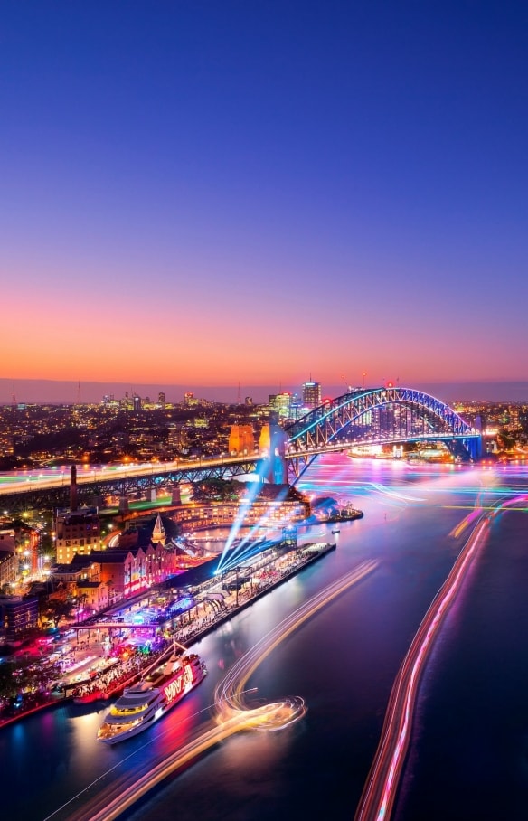 Aerial view over a harbour city adorned in rainbow lights during Vivid Sydney, Sydney, New South Wales © Destination NSW