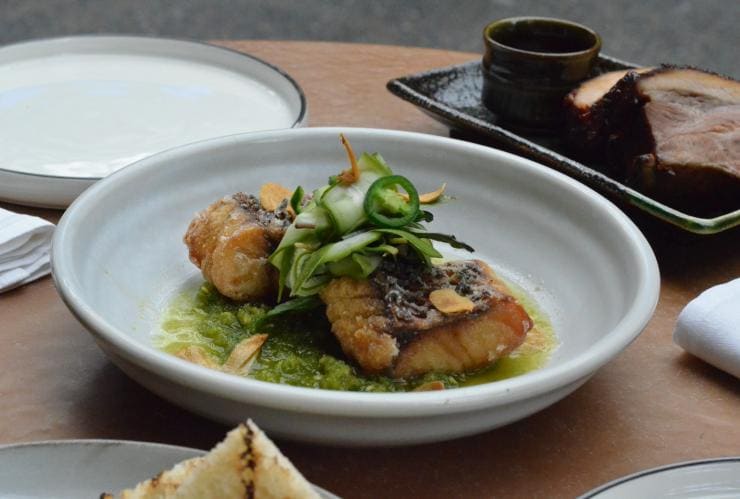 Barramundi cotto su un letto di verdure ricoperto di cetrioli e jalapenos al The Smith, Melbourne, Victoria © The Smith